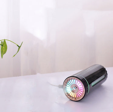 GlowMist USB diffuser emitting aromatic mist on a wooden desk